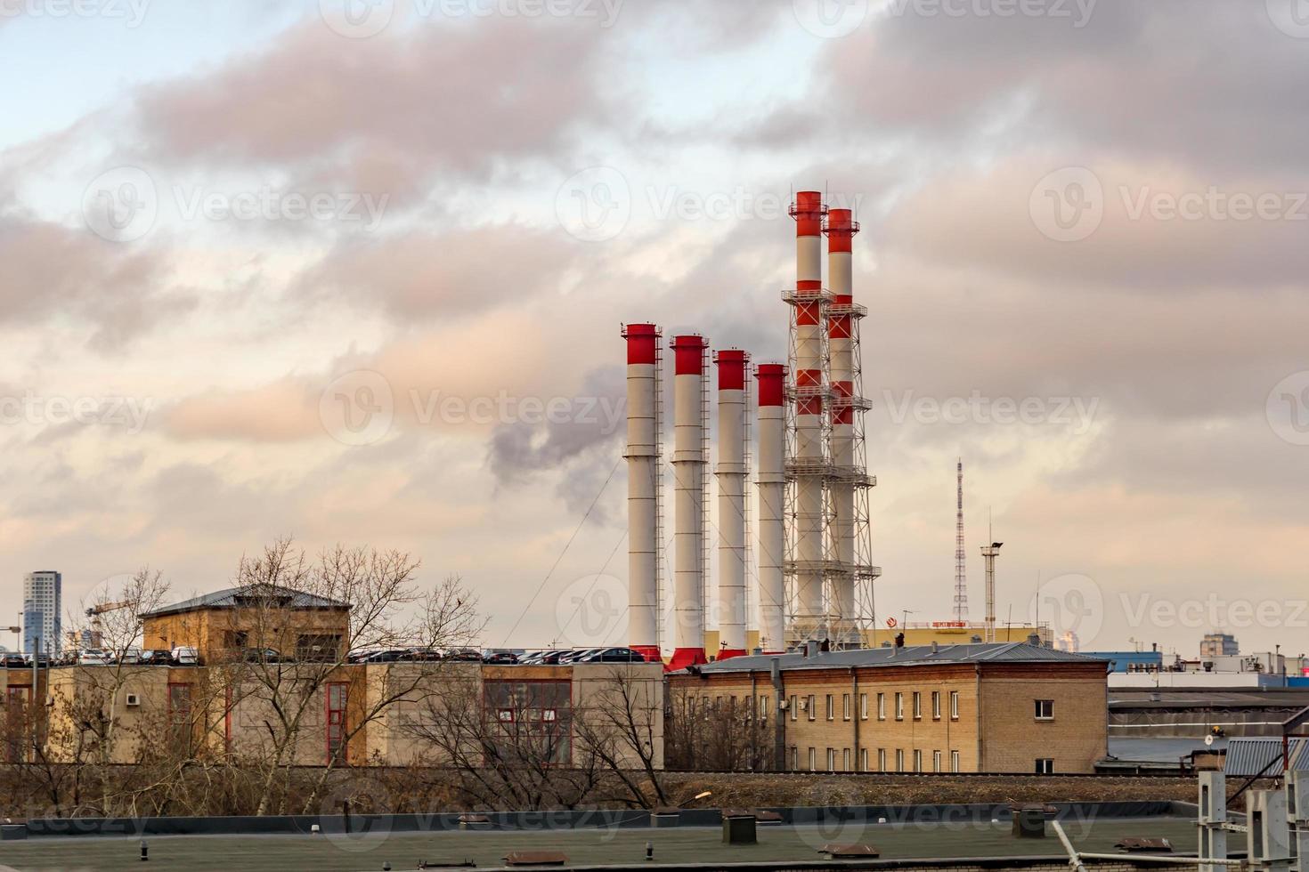 View of industrial city - old red and white smoke stacks on sunset sky background photo