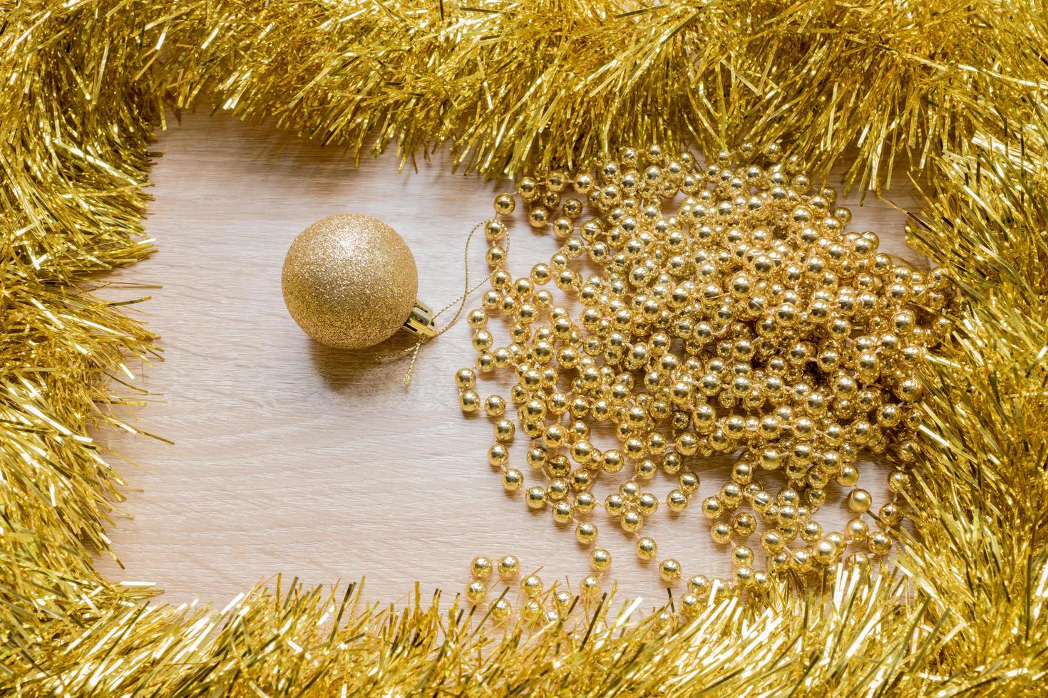 Christmas New Year holiday background. Golden tinsel, sparkle ball and garland on wooden background photo