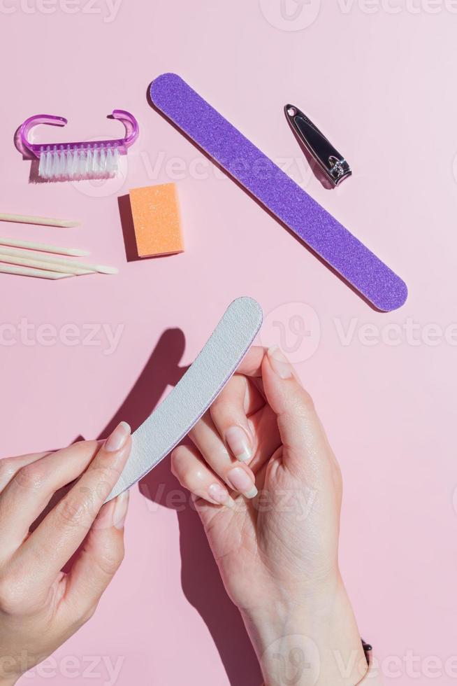 Woman aligns her nails with a nail file. Alignment of the nail edge. Manicure at home for yourself. A woman's hand with healthy natural nails. procedure of nail care. Top view. photo