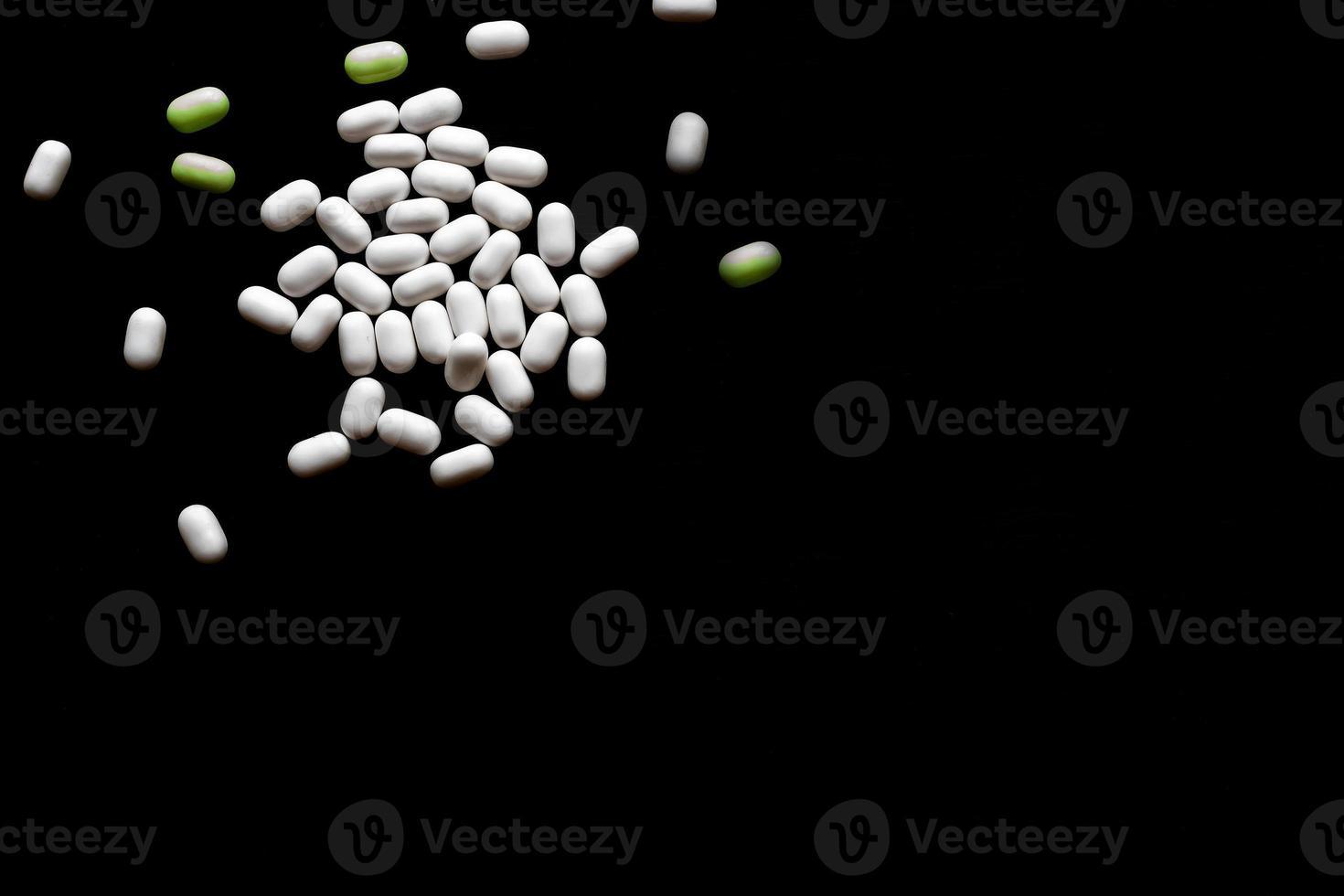 white and green pills On black wooden background with copy space photo