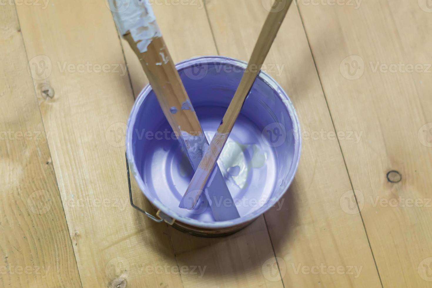 empty paint can with wooden sticks on wooden floor photo