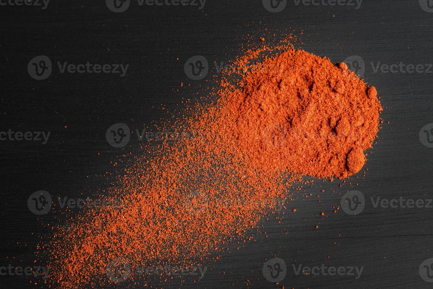 paprika powder on black background, top view photo