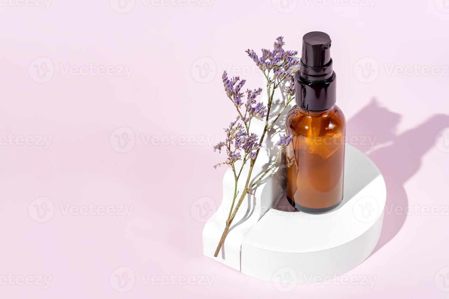 Amber glass bottle with pomp lid on the white podiums. Pink background. Container mockup with face cream or serum. Showcase for the presentation skincare products. photo