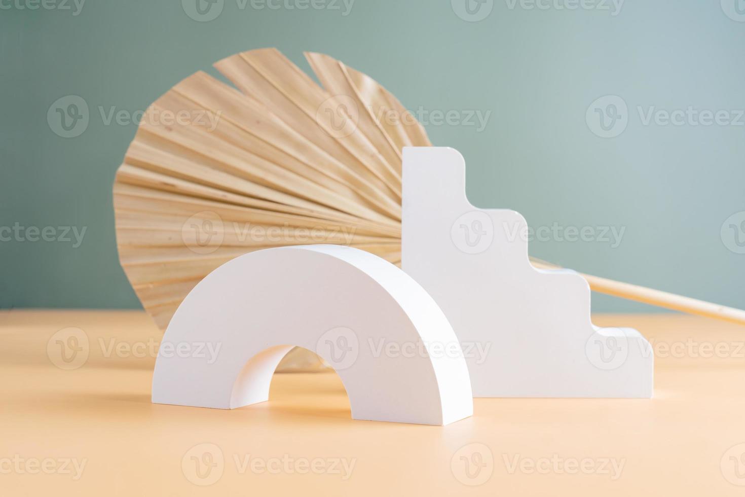 Empty white podium on beige and green background with dried palm leaf. Gypsum podium for the presentation of cosmetic products photo
