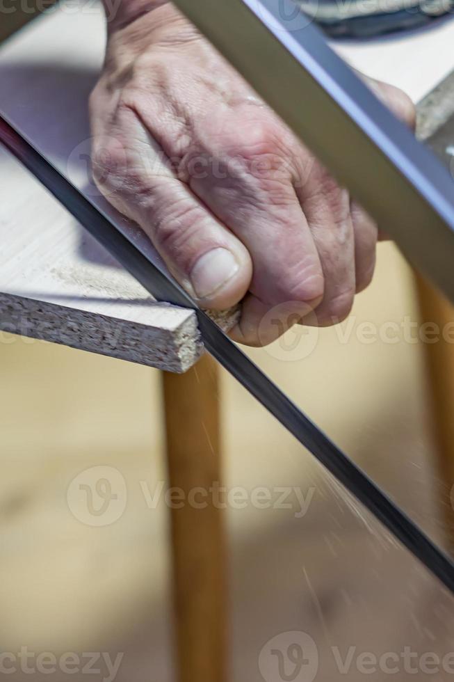 hombre aserrando una tabla con una sierra para metales foto