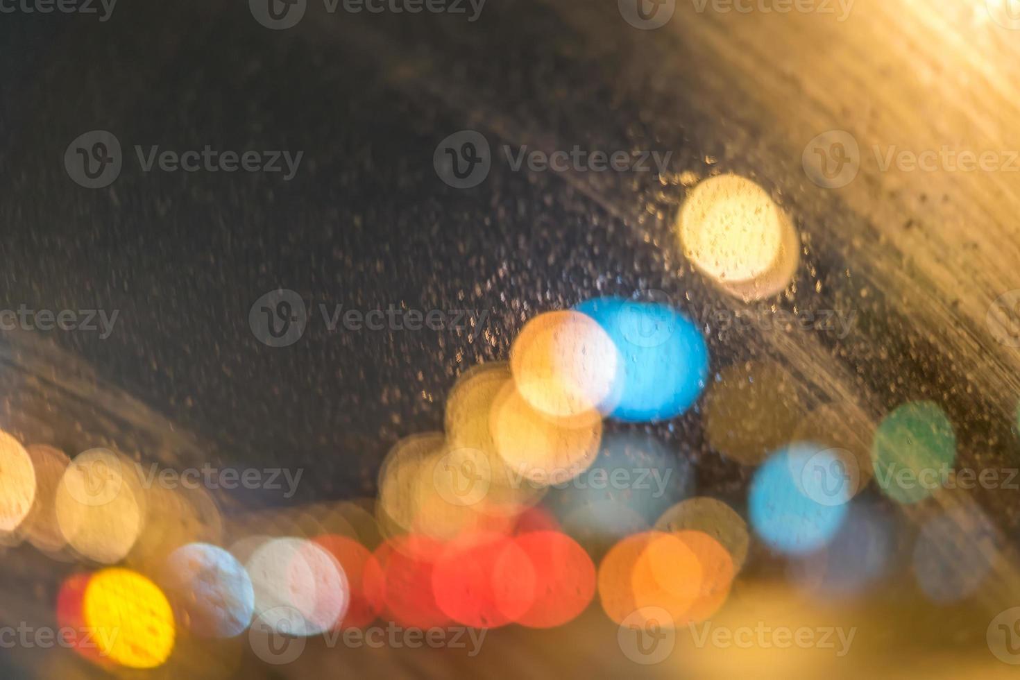 defocused road with lights through wet car window photo