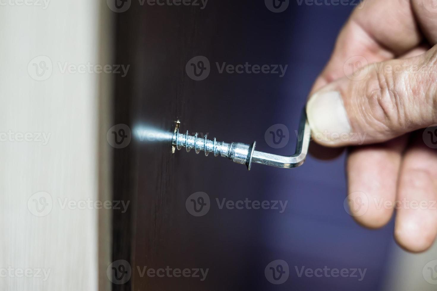 Assembling of furniture, closeup hex wrench in man hand photo