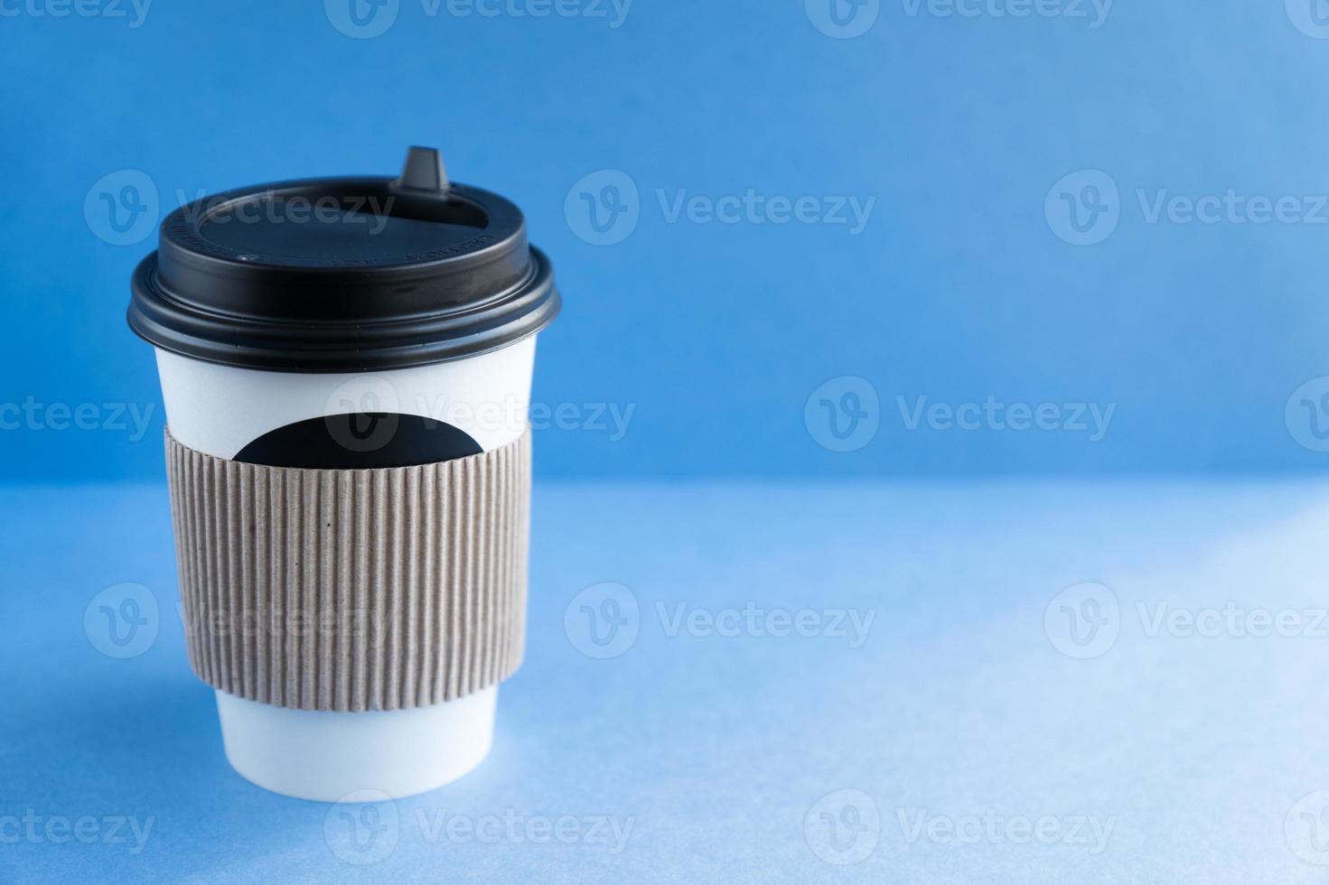 white paper kraft disposable cup for coffee with black plastic lid. coffe to go on blue background. photo