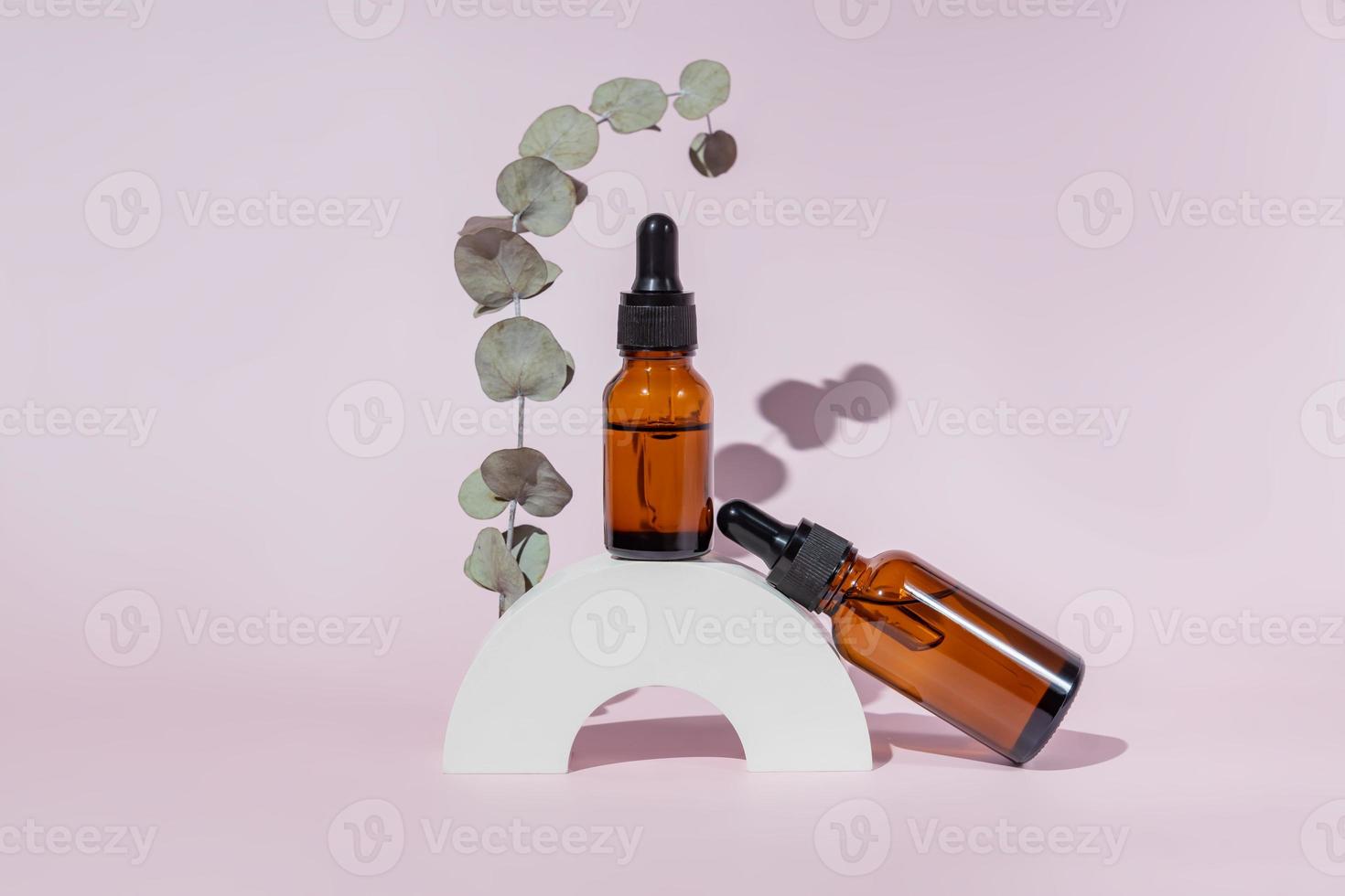 Natural skincare product in glass bottles with dropper. Serum for woman facial skin. Herbal mineral cosmetic on white concrete stand. Dark glass package cosmetology with pipette. Copy space. photo