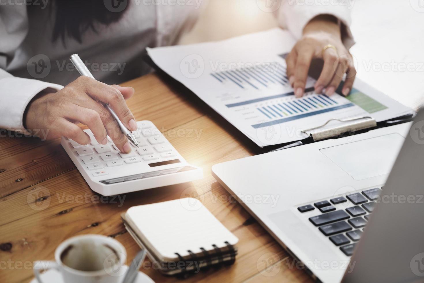 Business woman using calculator to review balance sheet annual  using  document and laptop computer to calculating budget. audit and Check integrity before investment concept. photo