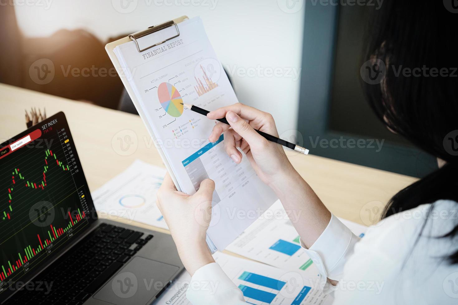 Business owner holding a pencil pointing to financial documents to analyze the profits of third parties to invest in company stocks. photo