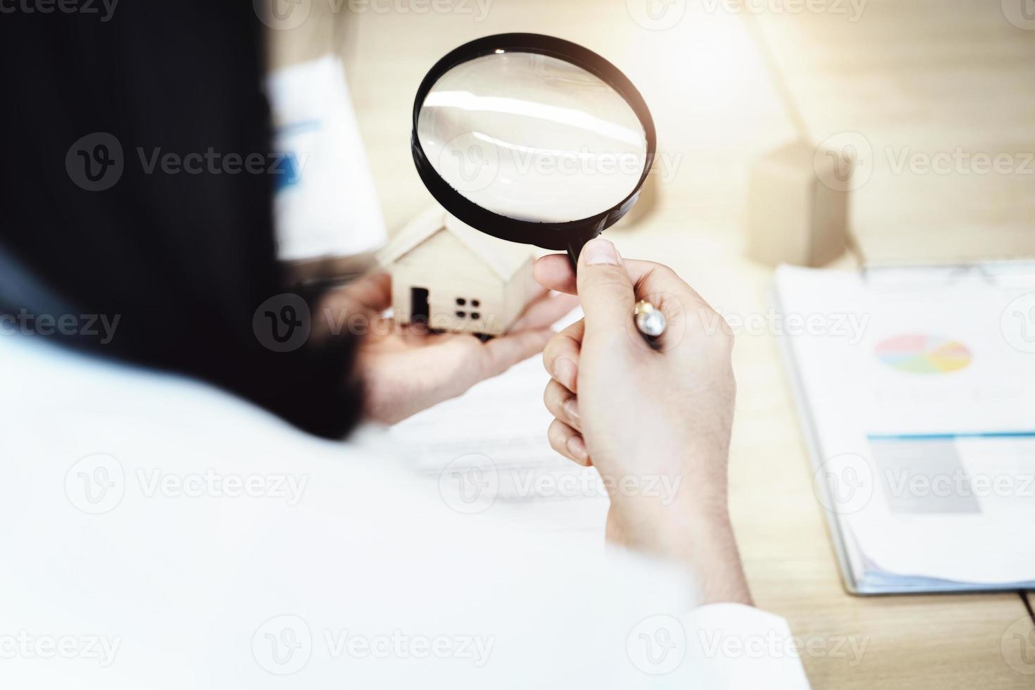 Inspector Concept, a customer is holding a magnifying glass to look at each house model to check the price of a home loan for each model. photo