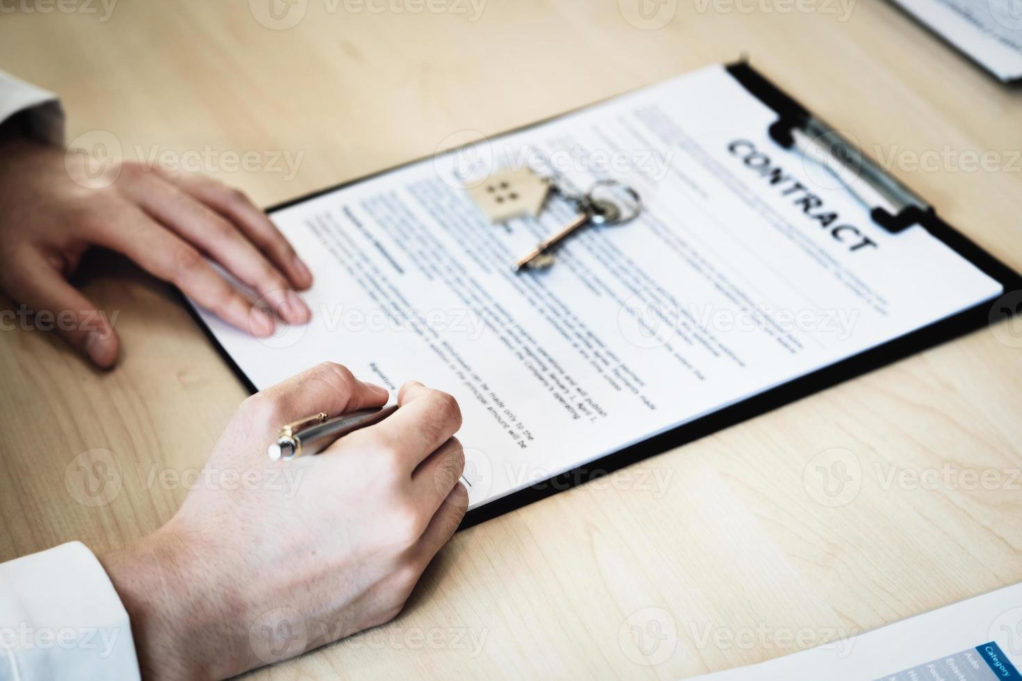The customer is holding a pen and is reading the housing purchase contract before signing it. photo