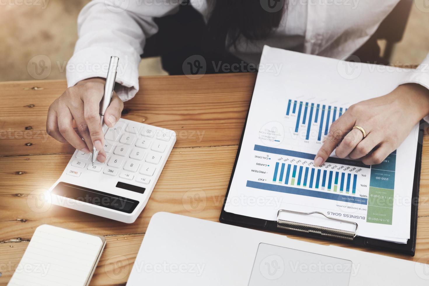 Business woman using calculator to review balance sheet annual  using  document and laptop computer to calculating budget. audit and Check integrity before investment concept. photo