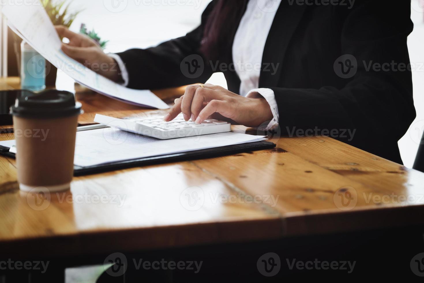 Business woman using calculator to review balance sheet annual  using  document and laptop computer to calculating budget. audit and Check integrity before investment concept. photo