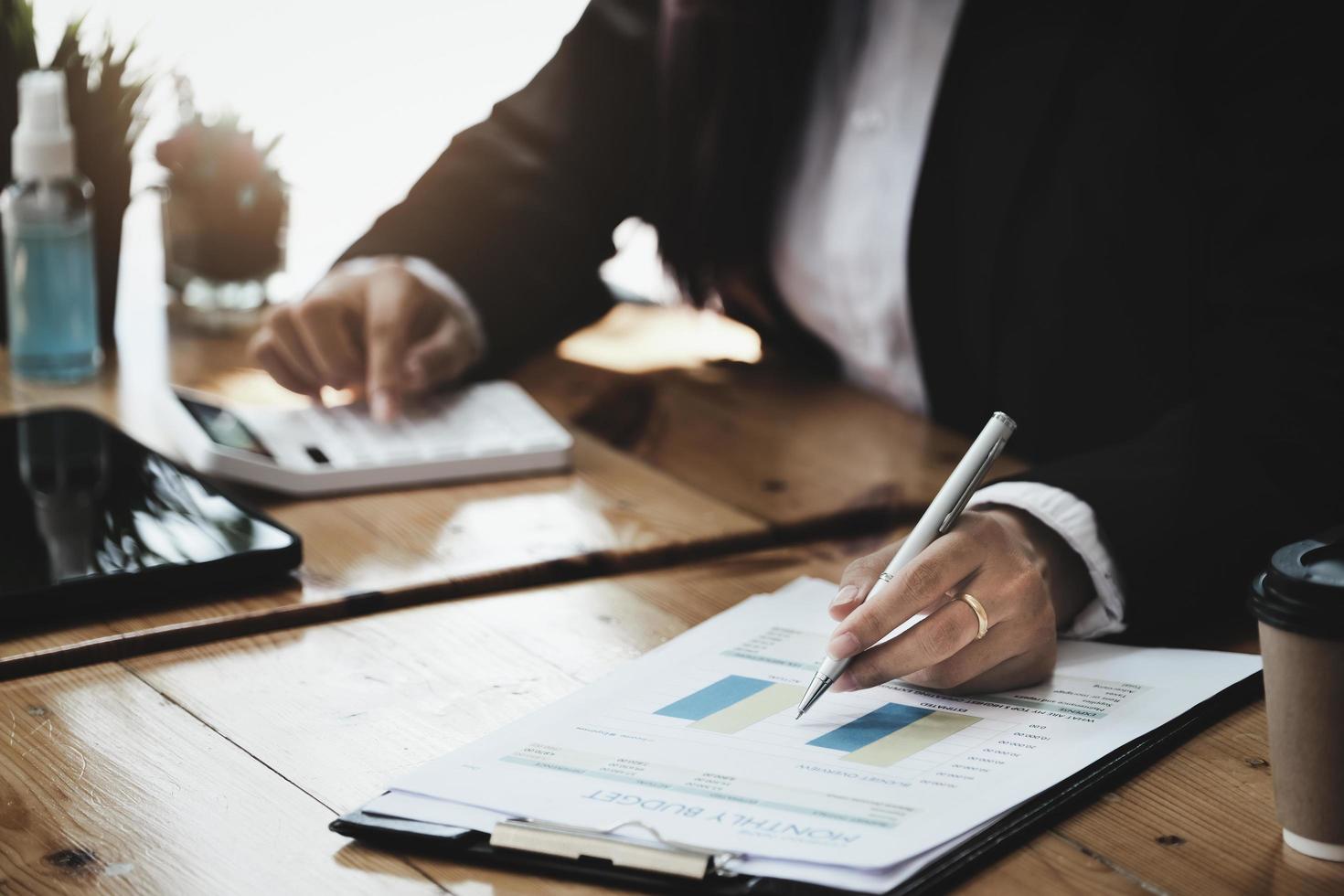 A businesswoman examines financial documents and uses a calculator to research the income affected by the coronavirus pandemic to adjust her marketing strategy. photo