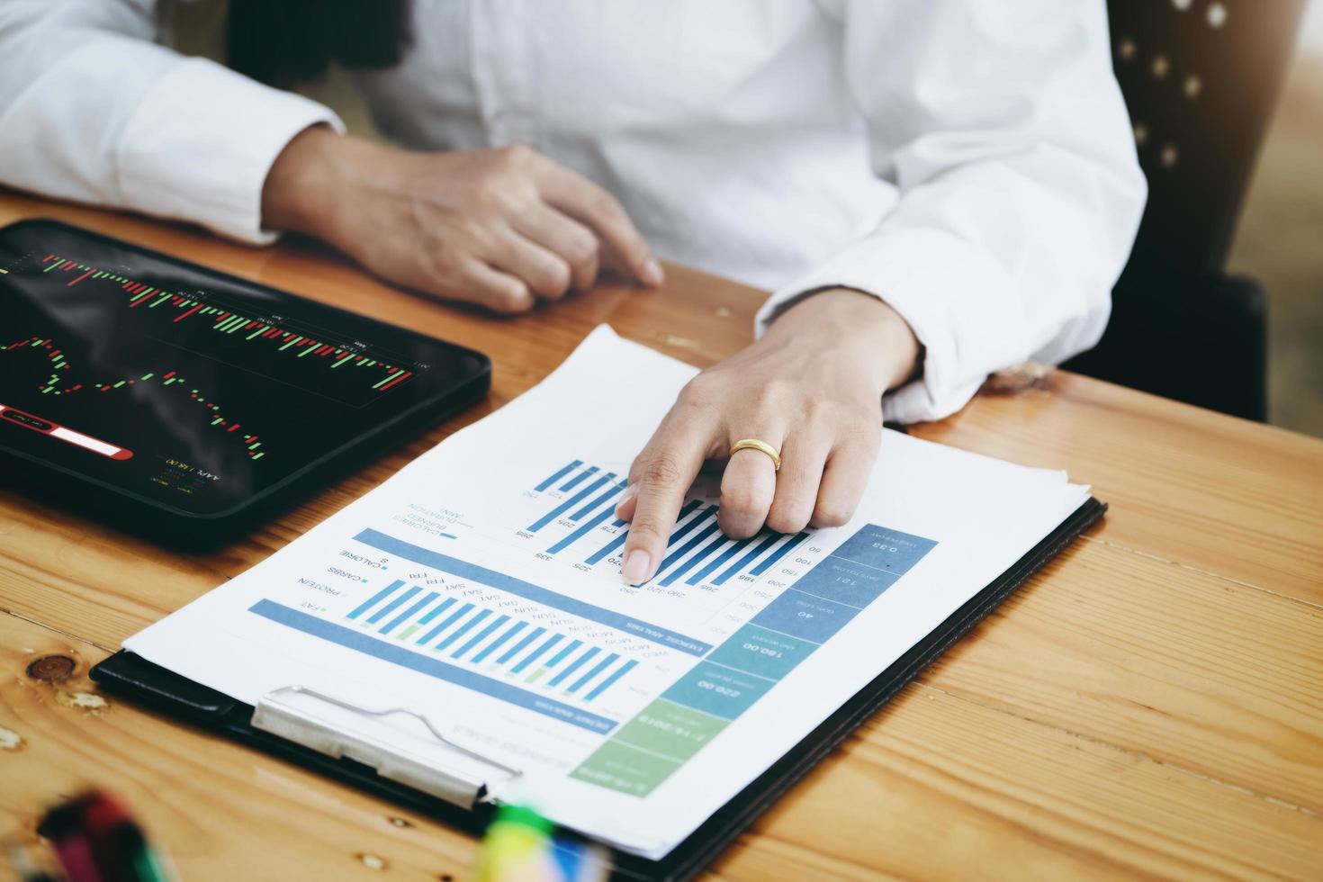 New normal, self-employed women pointing document stock and using a tablet to trade stocks for profit, buying and selling. photo