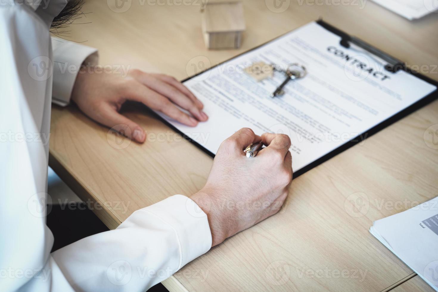 el cliente sostiene un bolígrafo y lee el contrato de compra de vivienda antes de firmarlo. foto