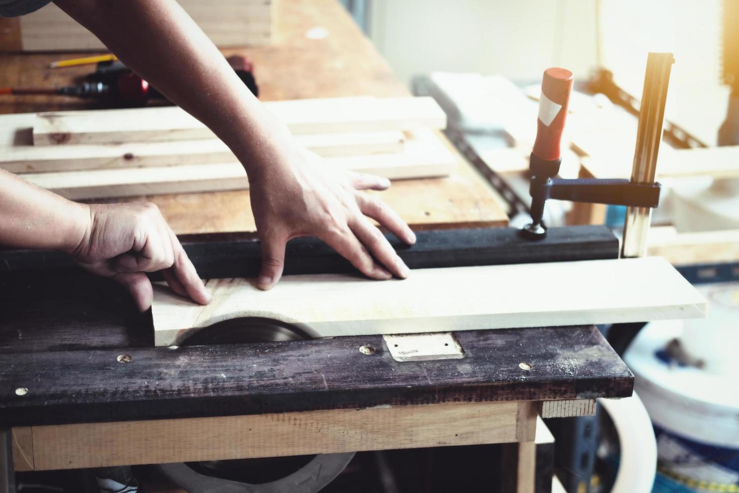 Woodworking practitioners use saw blades to cut wood pieces to assemble and build wooden tables for their clients. photo