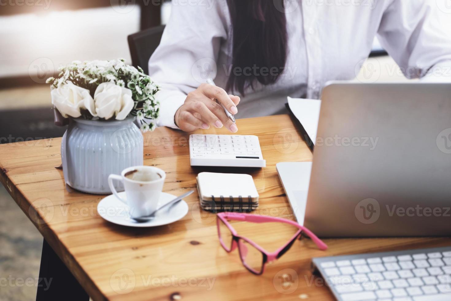 Business woman using calculator to review balance sheet annual  using  document and laptop computer to calculating budget. audit and Check integrity before investment concept. photo