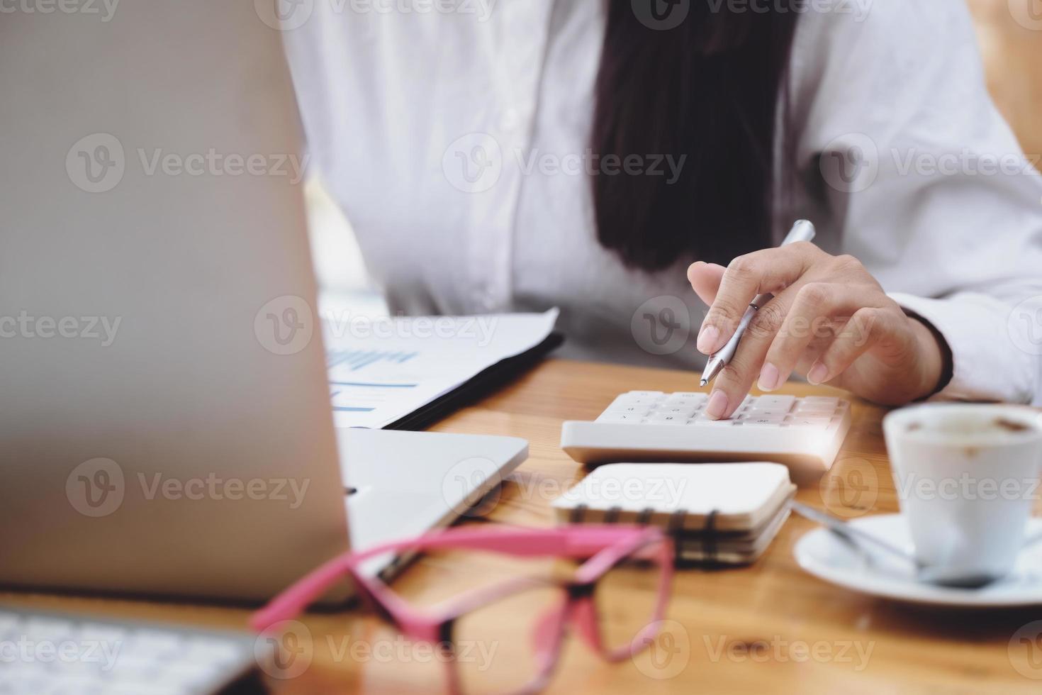 Business woman using calculator to review balance sheet annual  using  document and laptop computer to calculating budget. audit and Check integrity before investment concept. photo