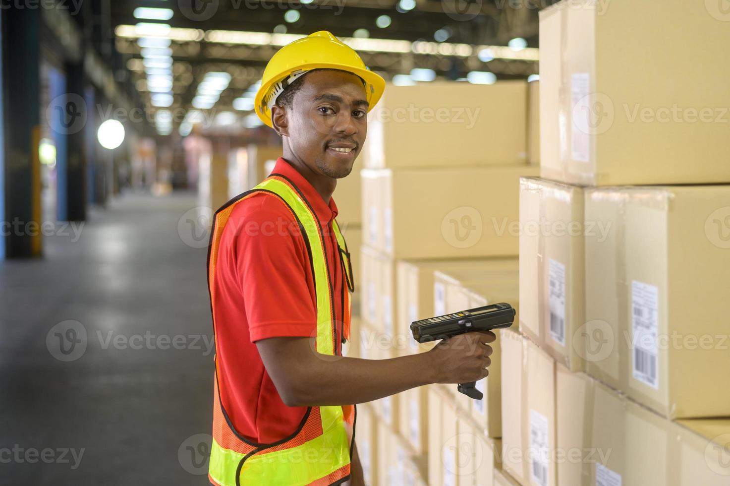 joven trabajador con casco escaneando paquetes para el envío minorista y de transporte en un almacén moderno. foto