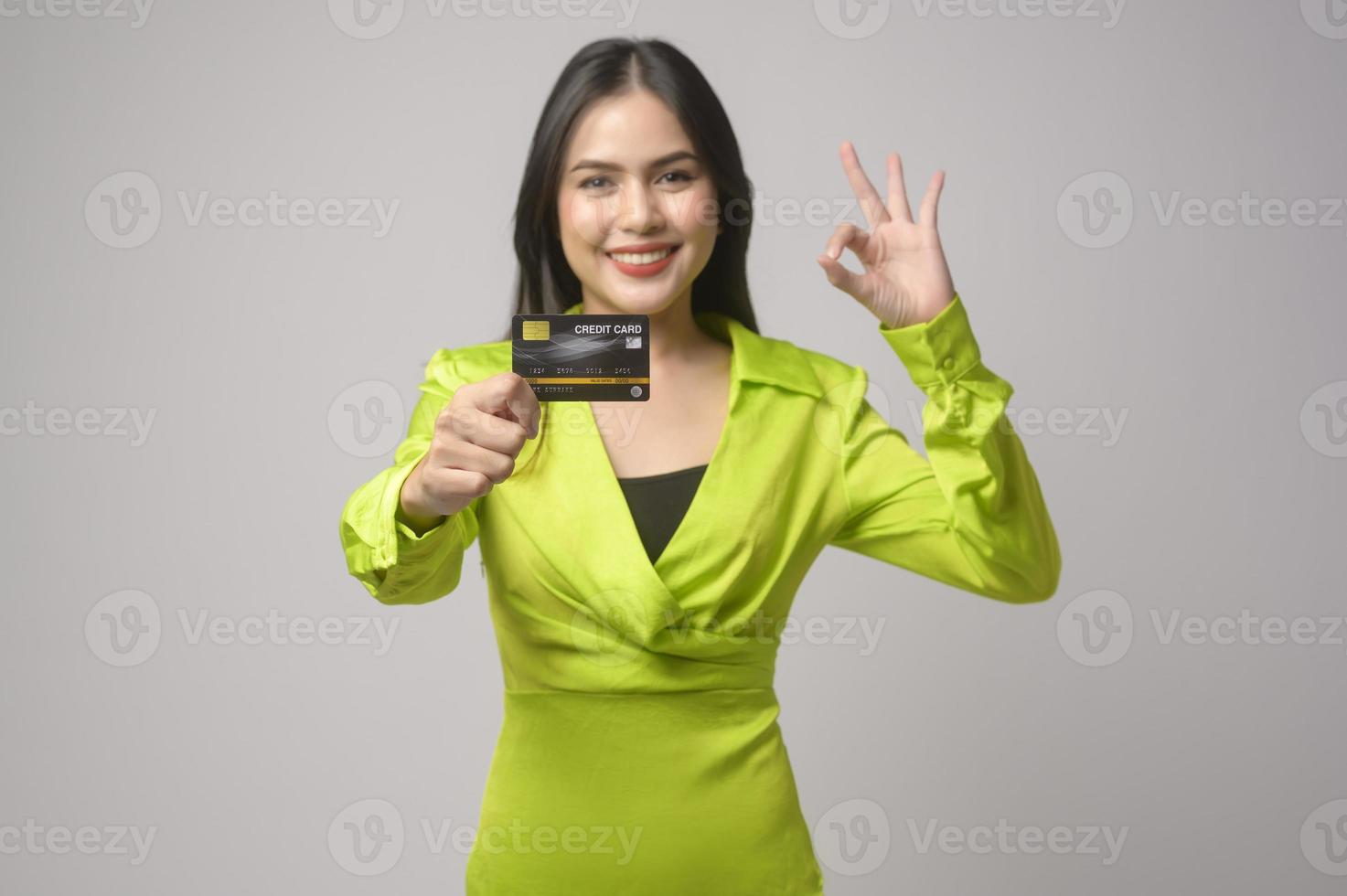 Beautiful woman holding credit card over white background studio, shopping and finance concept. photo