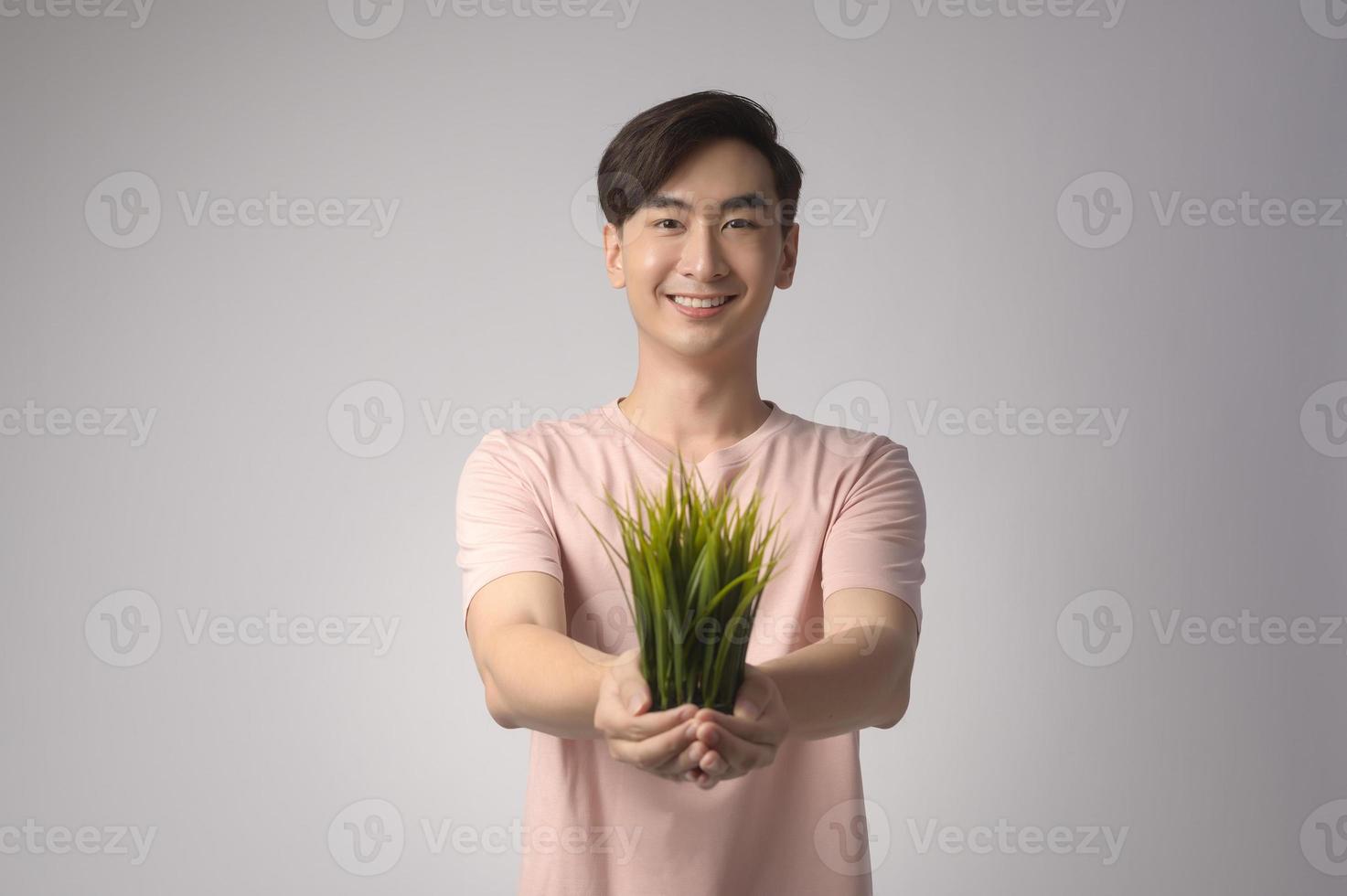 joven sonriente sosteniendo un árbol sobre un estudio de fondo blanco, salvar el concepto de tierra foto