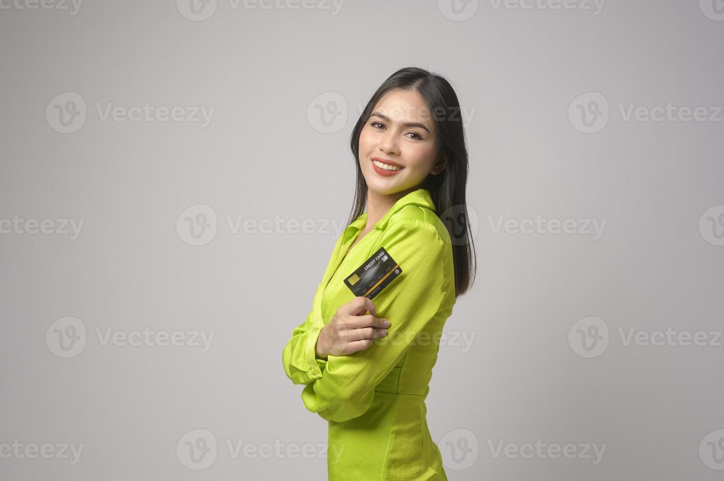 Beautiful woman holding credit card over white background studio, shopping and finance concept. photo