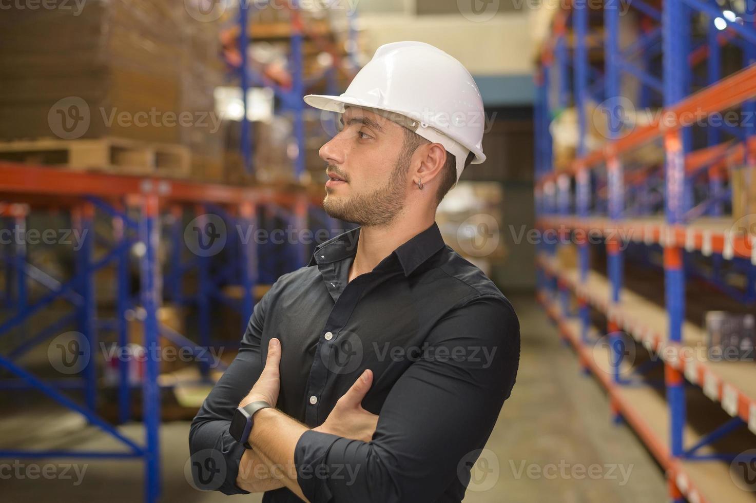 Portrait of young caucasian male worker wearing helmet in modern warehouse storage of retail shop photo