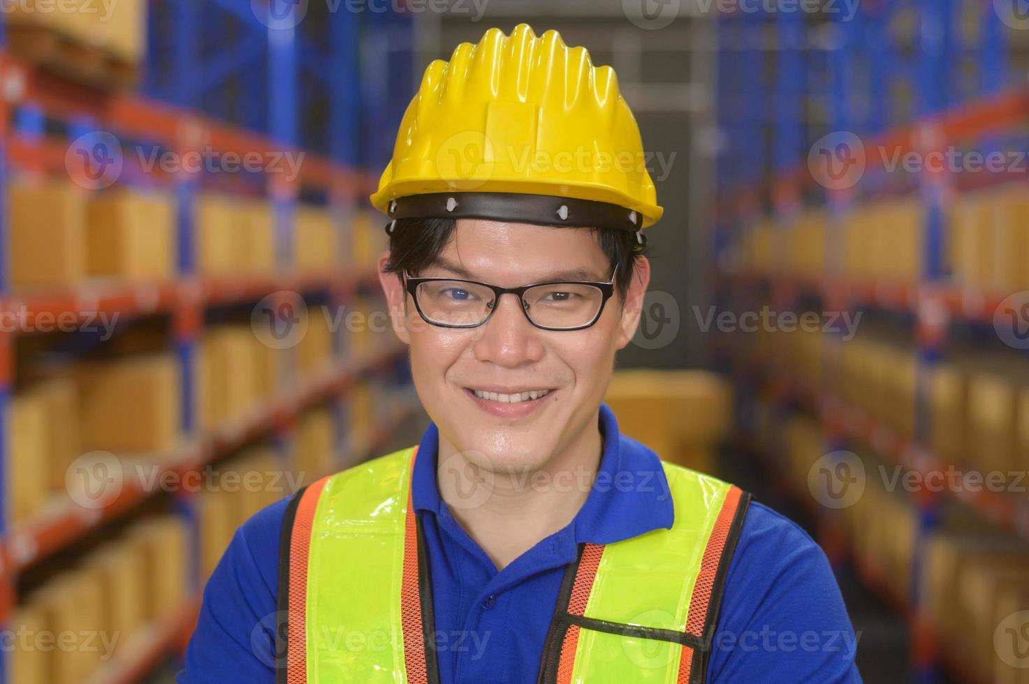 Portrait of young asian male worker wearing helmet in modern warehouse storage of retail shop photo