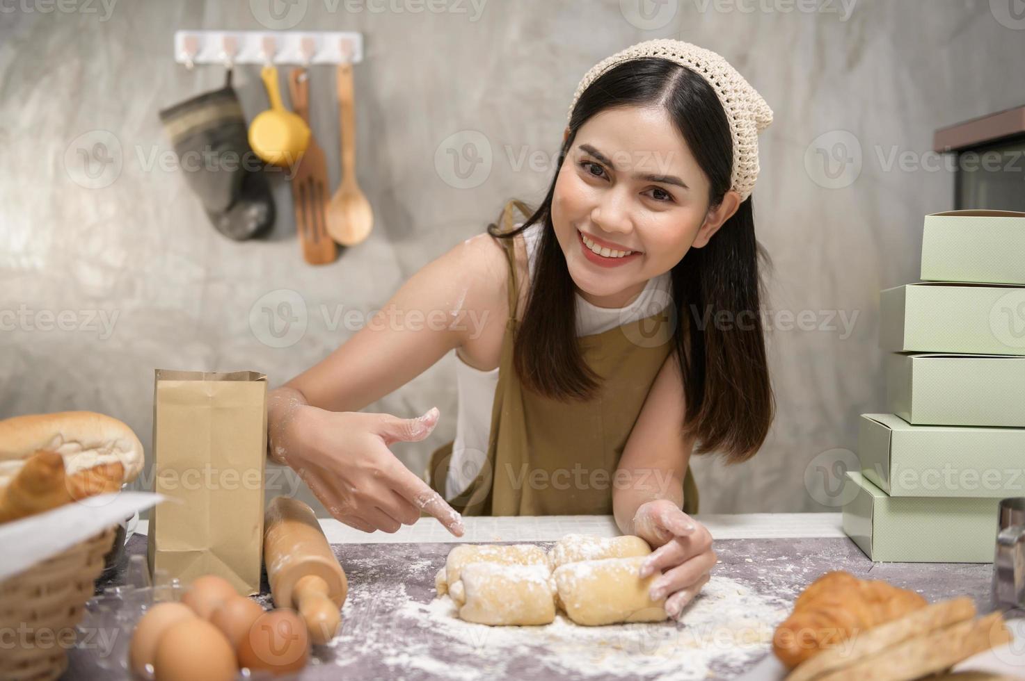 joven hermosa mujer está horneando en su negocio de cocina, panadería y cafetería foto