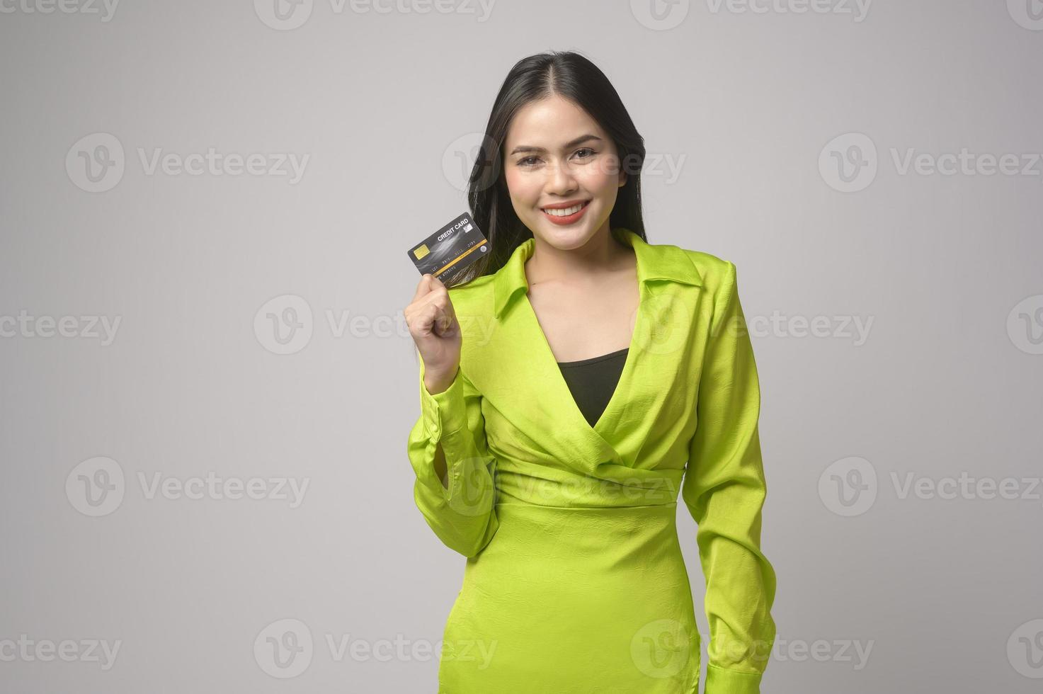 Beautiful woman holding credit card over white background studio, shopping and finance concept. photo