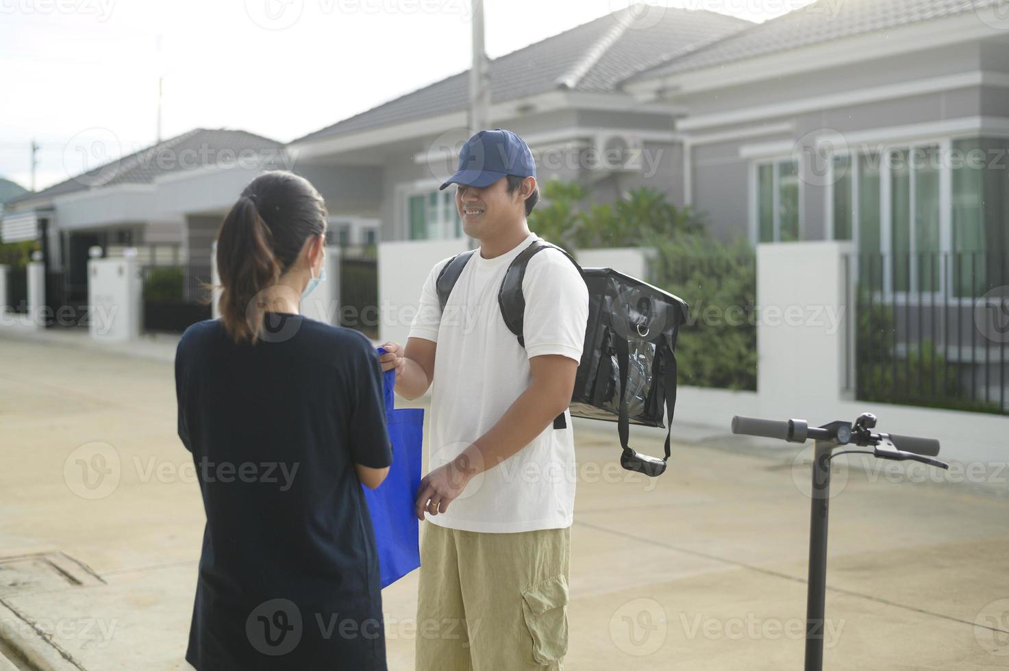 Smiling delivery man with thermal backpack riding on an electric scooter, deliver online concept photo