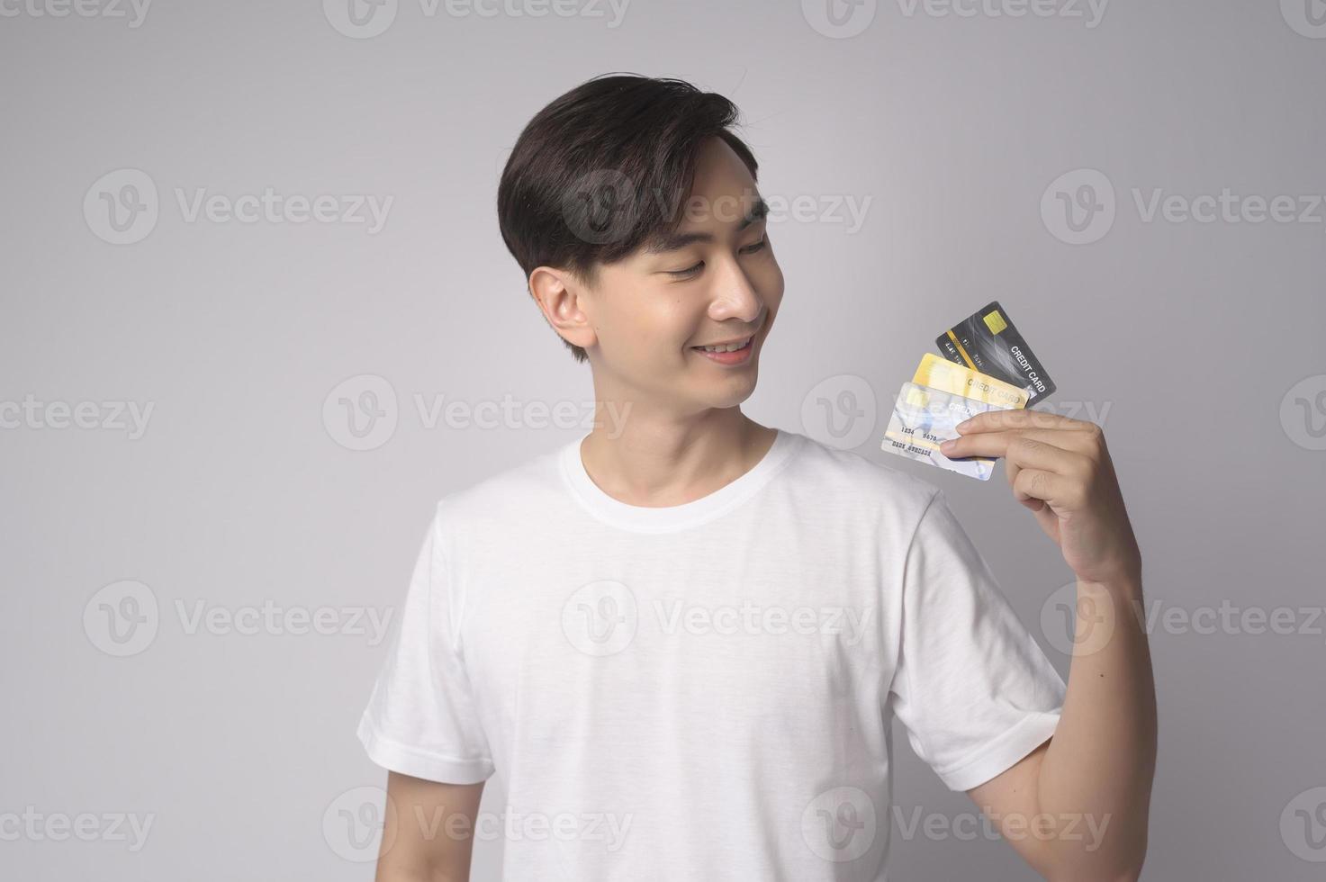 Young asian man holding credit card over white background studio, shopping and finance concept. photo