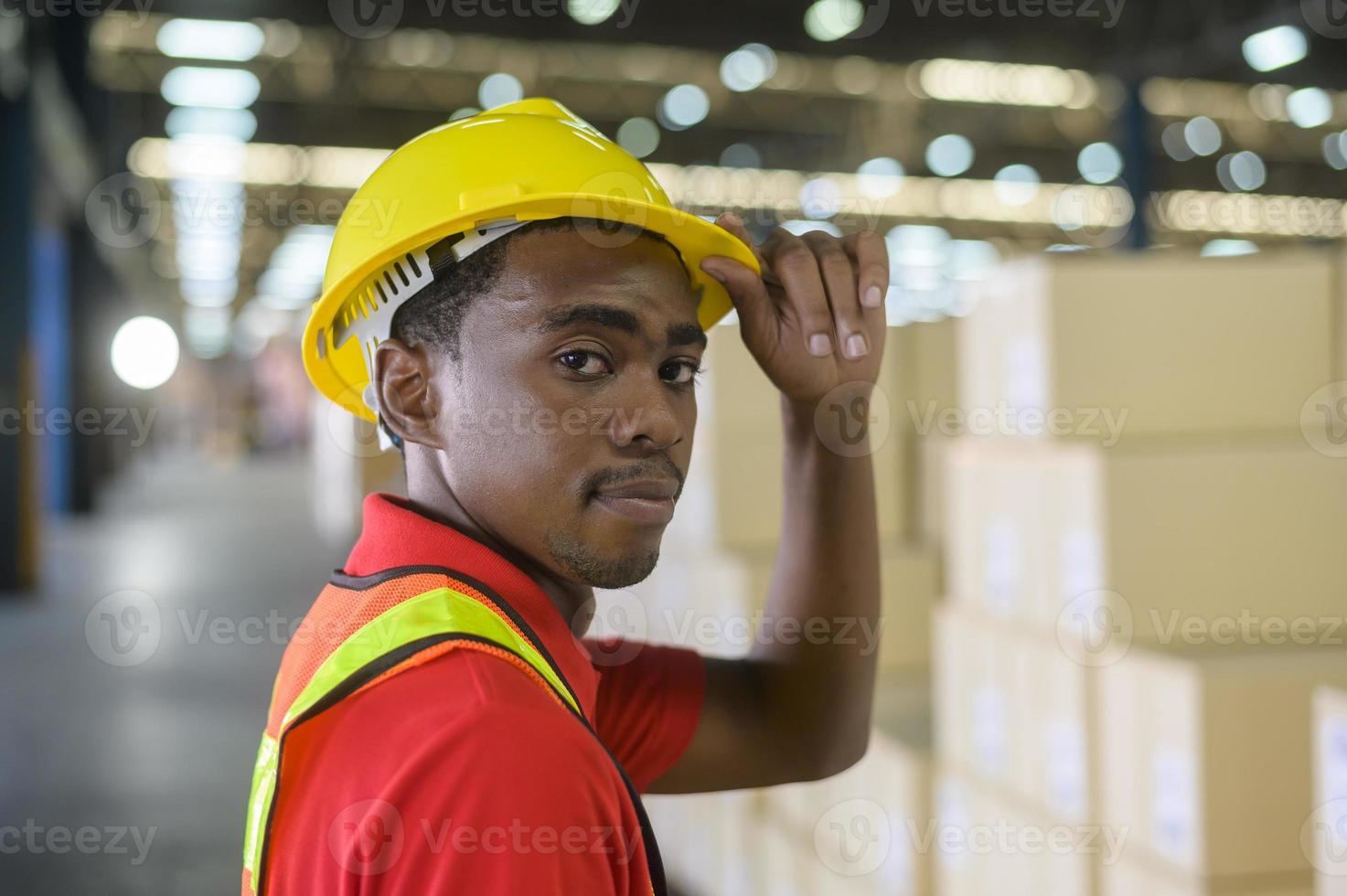 Portrait of young mixed race male worker wearing helmet in modern warehouse storage of retail shop photo