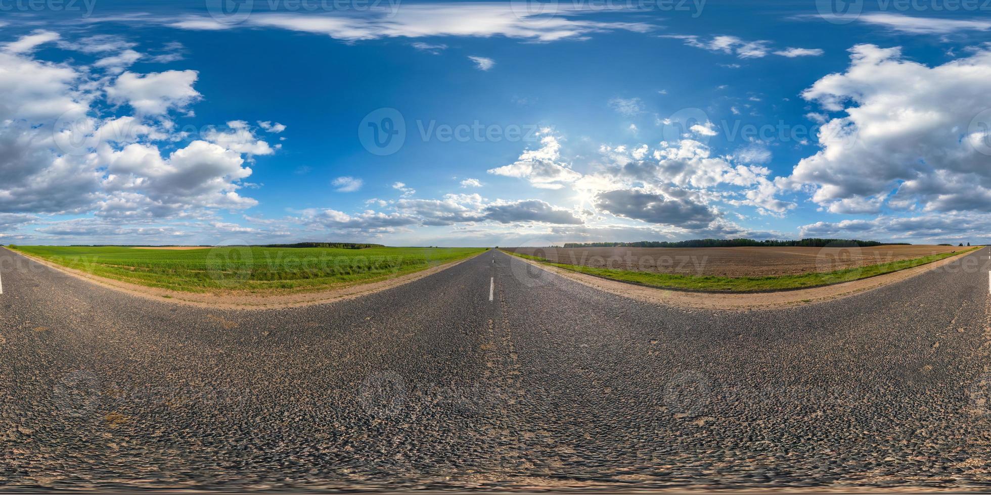 Full spherical seamless panorama 360 degrees angle view on no traffic asphalt road among fields in evening  before sunset with cloudy sky in equirectangular projection, VR AR content photo