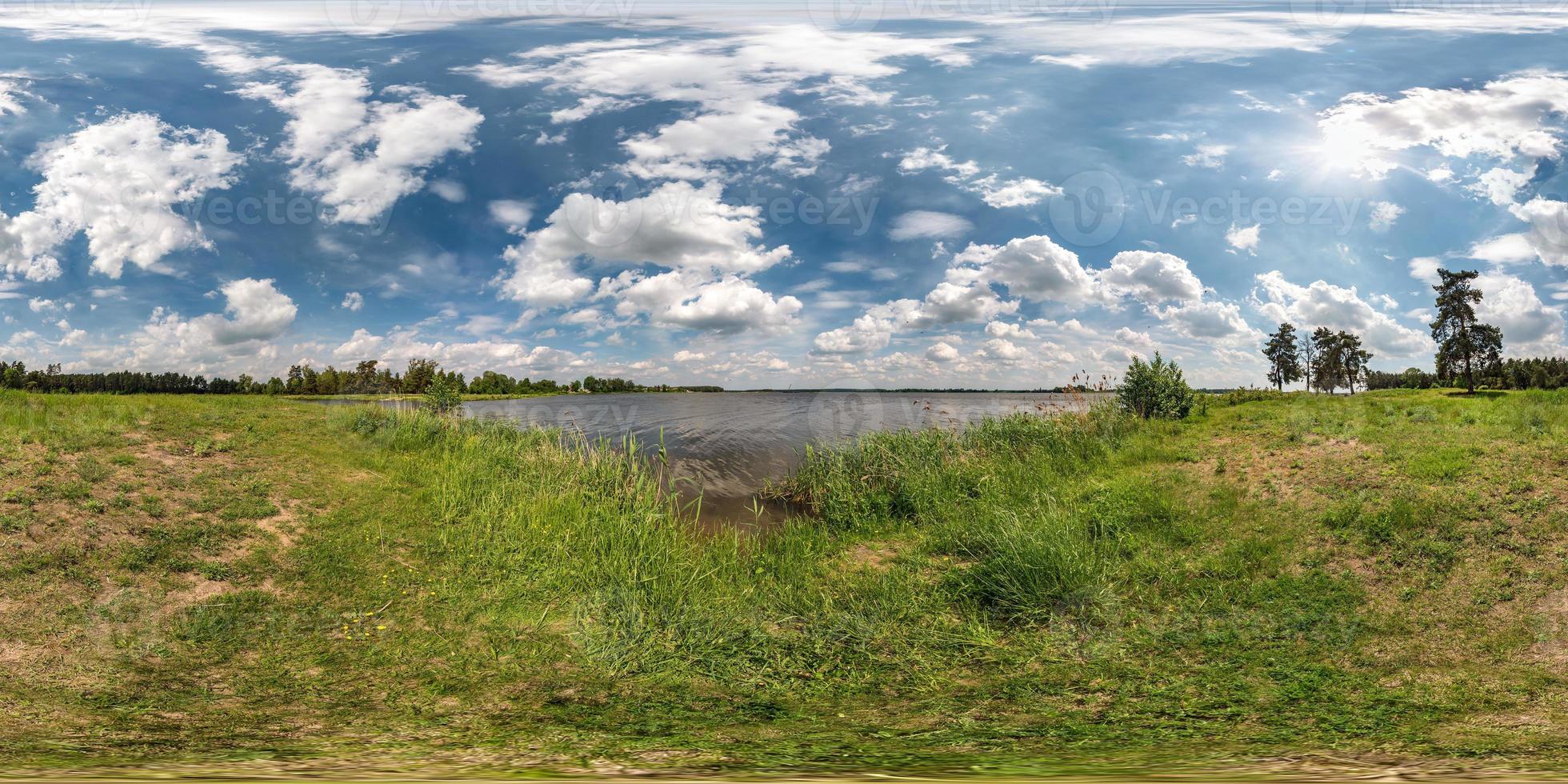 panorama hdri esférico completo sin costuras vista en ángulo de 360 grados en la costa de hierba de un gran lago o río en un día soleado de verano y clima ventoso con hermosas nubes en proyección equirectangular, contenido vr foto