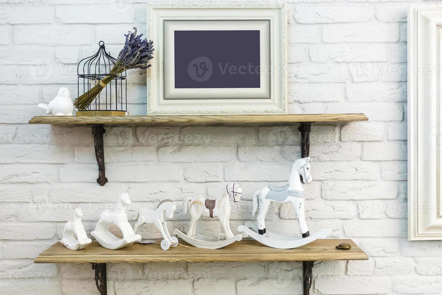 interior decoration toys. White decorative bird near cage and ceramic horses and foto frame in expensive interior photo