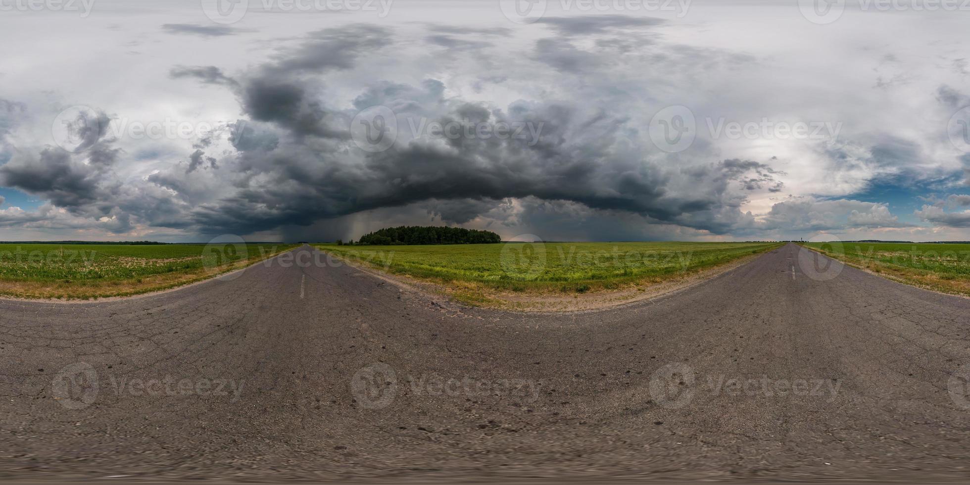 vista de ángulo de 360 grados de panorama hdr esférico completo en carretera asfaltada entre campos por la noche con impresionantes nubes negras antes de la tormenta en proyección equirectangular, vr ar contenido de realidad virtual foto