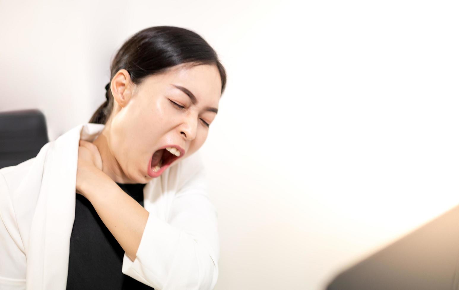 Asian young feeling painful from work, while sitting in front of the laptop in their home. Concept working woman office syndrome. photo