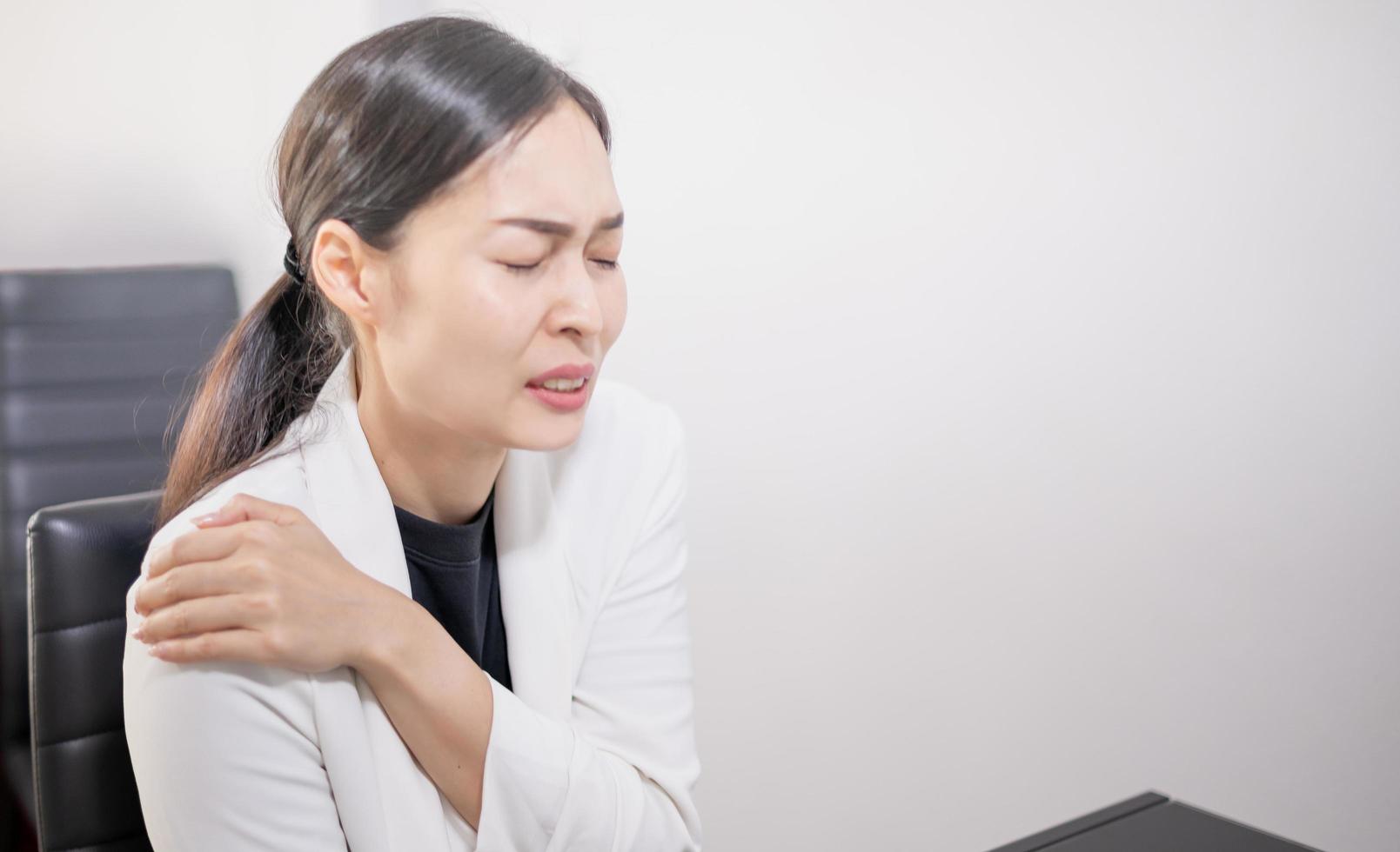 Asian young feeling painful from work, while sitting in front of the laptop in their home. photo