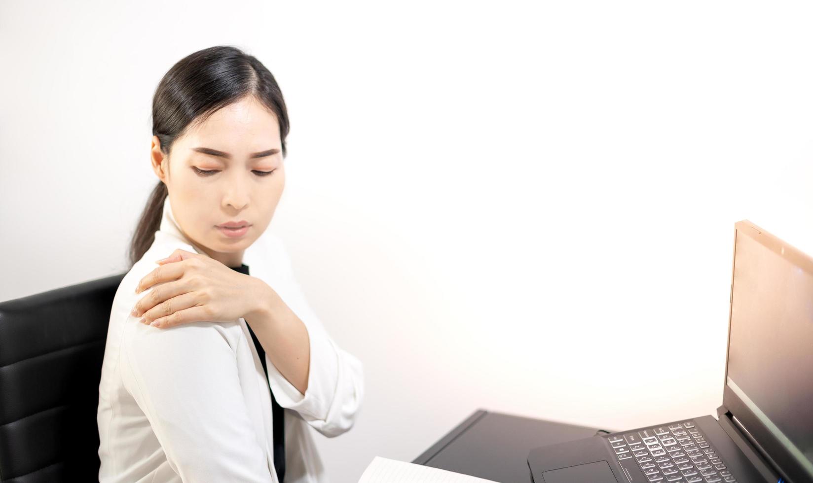 Asian young feeling painful from work, while sitting in front of the laptop in their home. Concept working woman office syndrome. photo