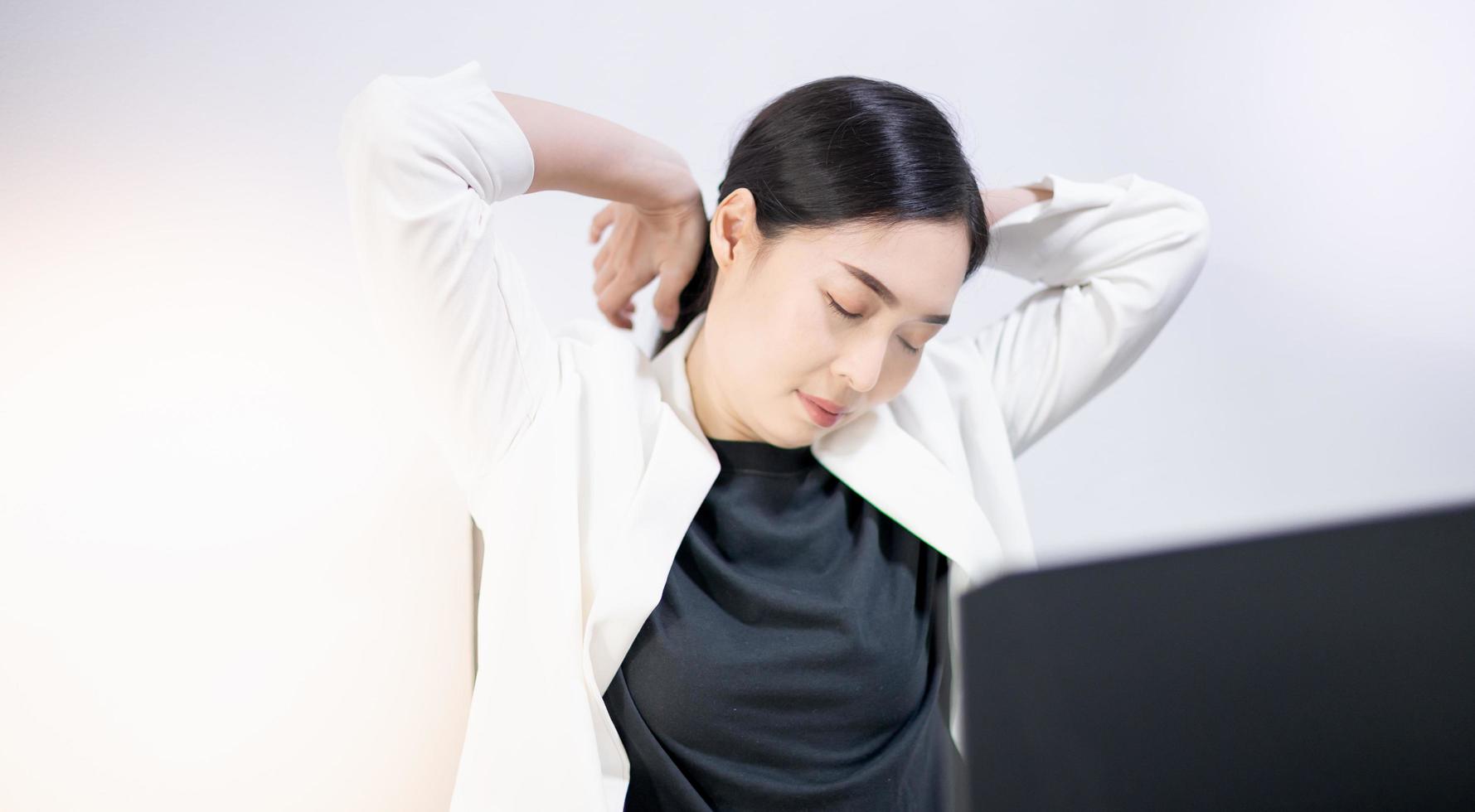 Asian young feeling painful from work, while sitting in front of the laptop in their home. Concept working woman office syndrome. photo