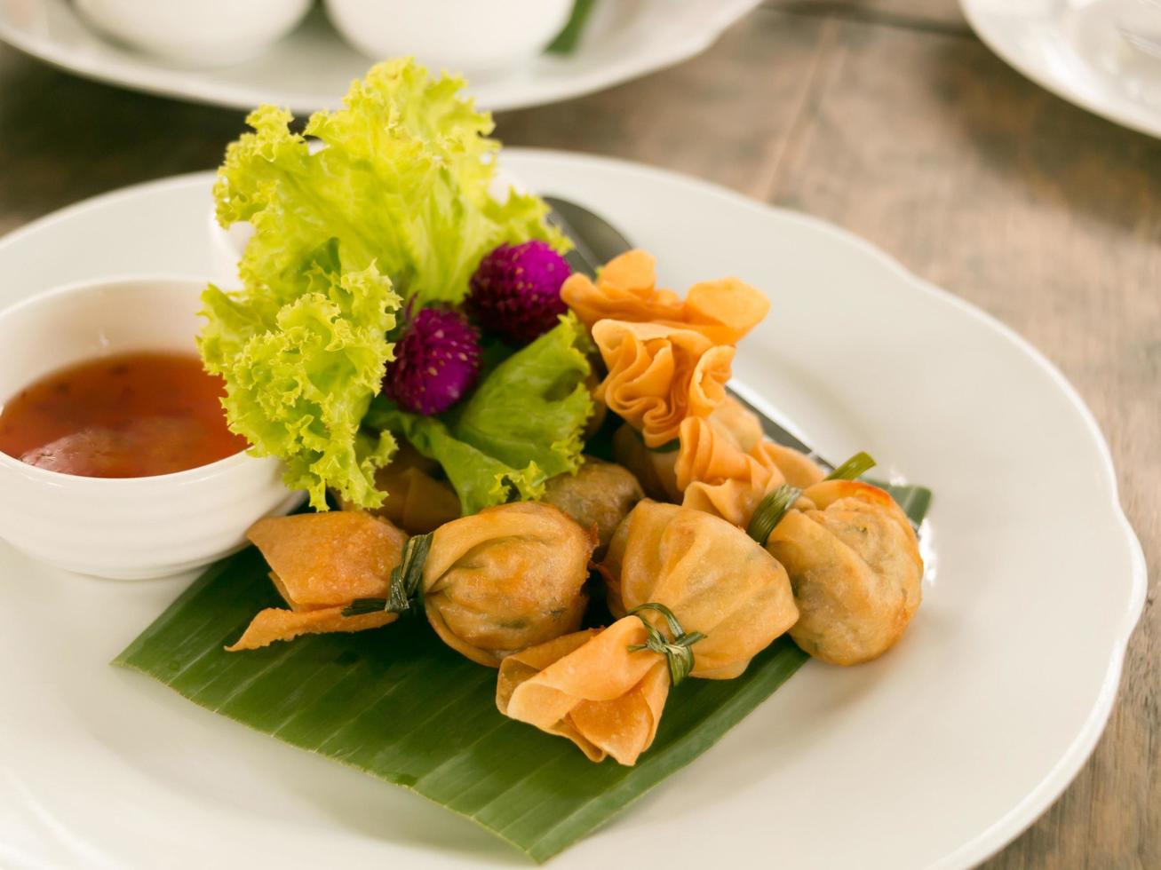The ancient Thai snack named Thung Thong with beautiful food decorated served on white plate with sweet sauce. photo