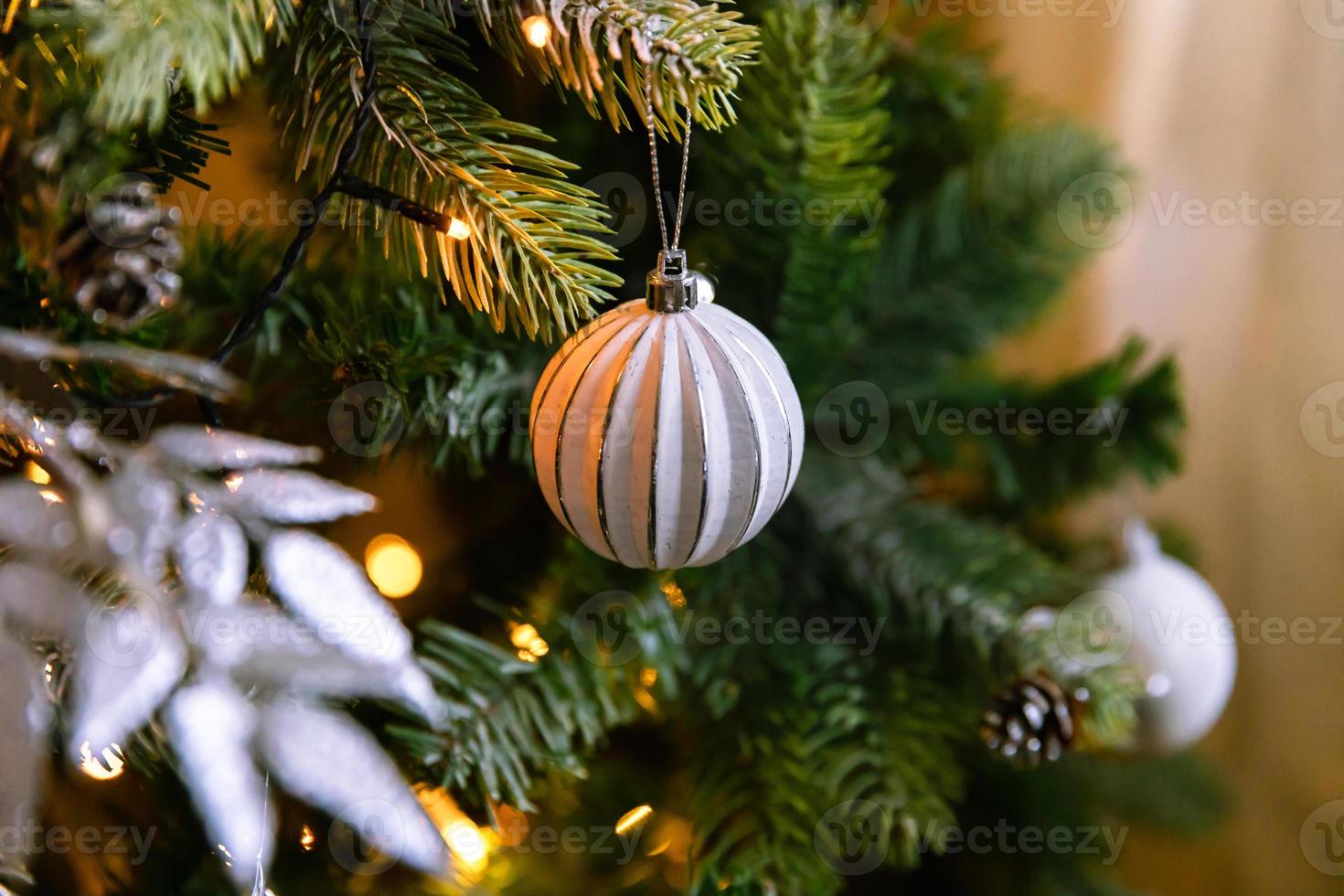 Classic Christmas decorated New year tree. Christmas tree with wite and silver decorations, ornaments toy and ball. Modern classical style interior design apartment. Christmas eve at home. photo