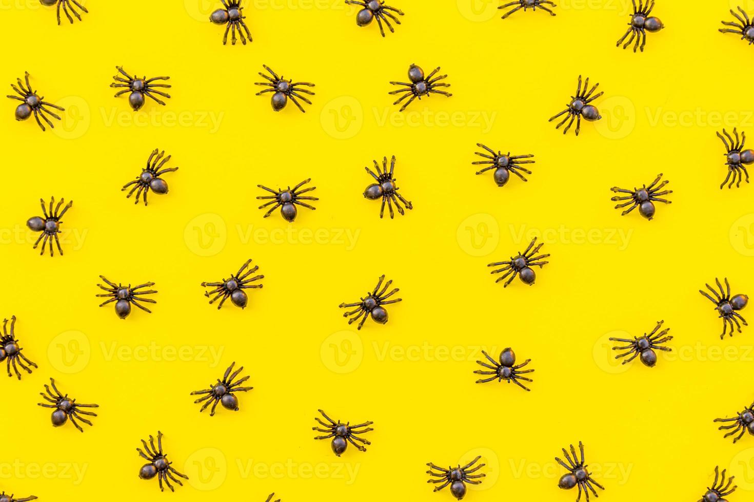 Halloween minimal decorations, composition with many black spiders isolated on yellow background. Halloween celebration trick or treat concept. Flat lay top view pattern. photo