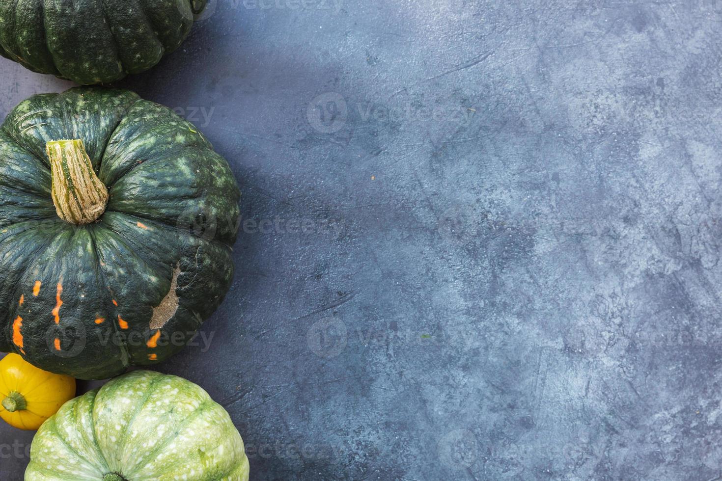 Autumnal Background. Natural autumn fall view pumpkins on dark black stone shale background. Change of seasons ripe organic food concept, Halloween party Thanksgiving day. Flat lay top view copy space photo
