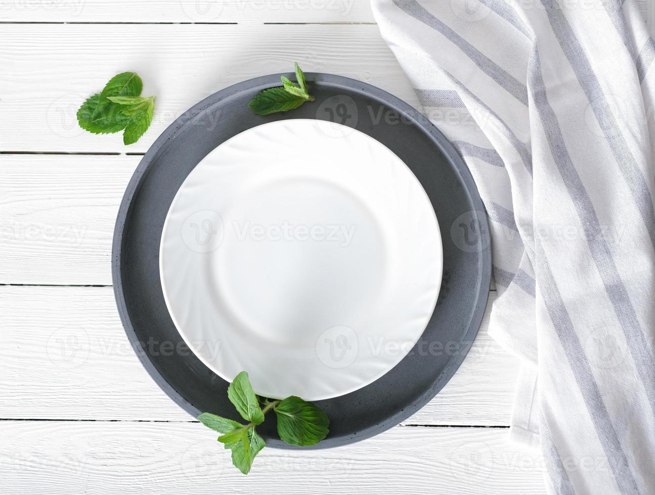 empty white plate on a table, dinner setting, mockup for food styling. tablecloth and cement round tray, top view photo