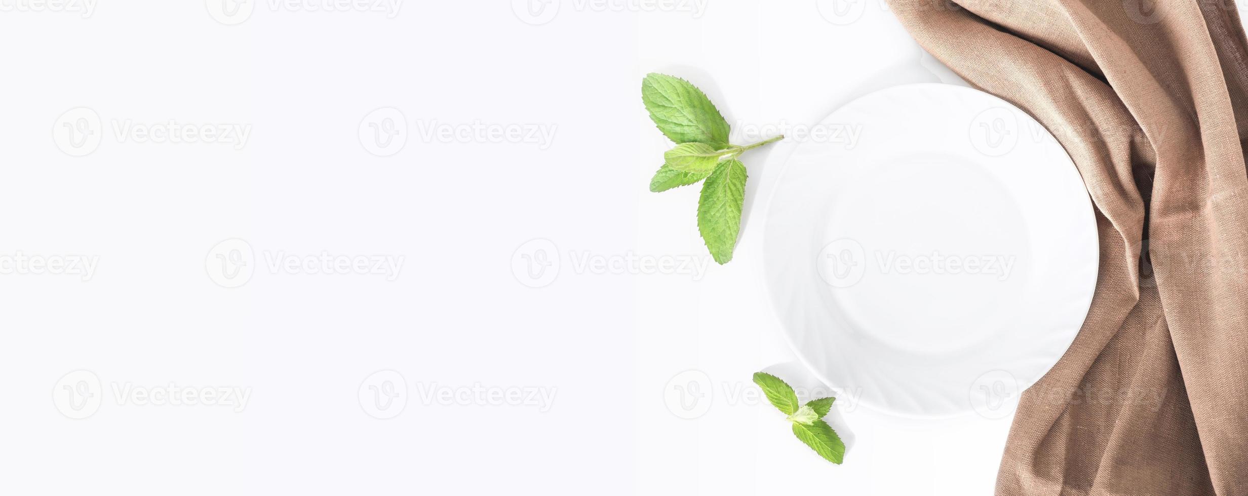 empty white plate on a table, dinner setting, mockup for food styling. tablecloth and green plants. Top view, banner photo